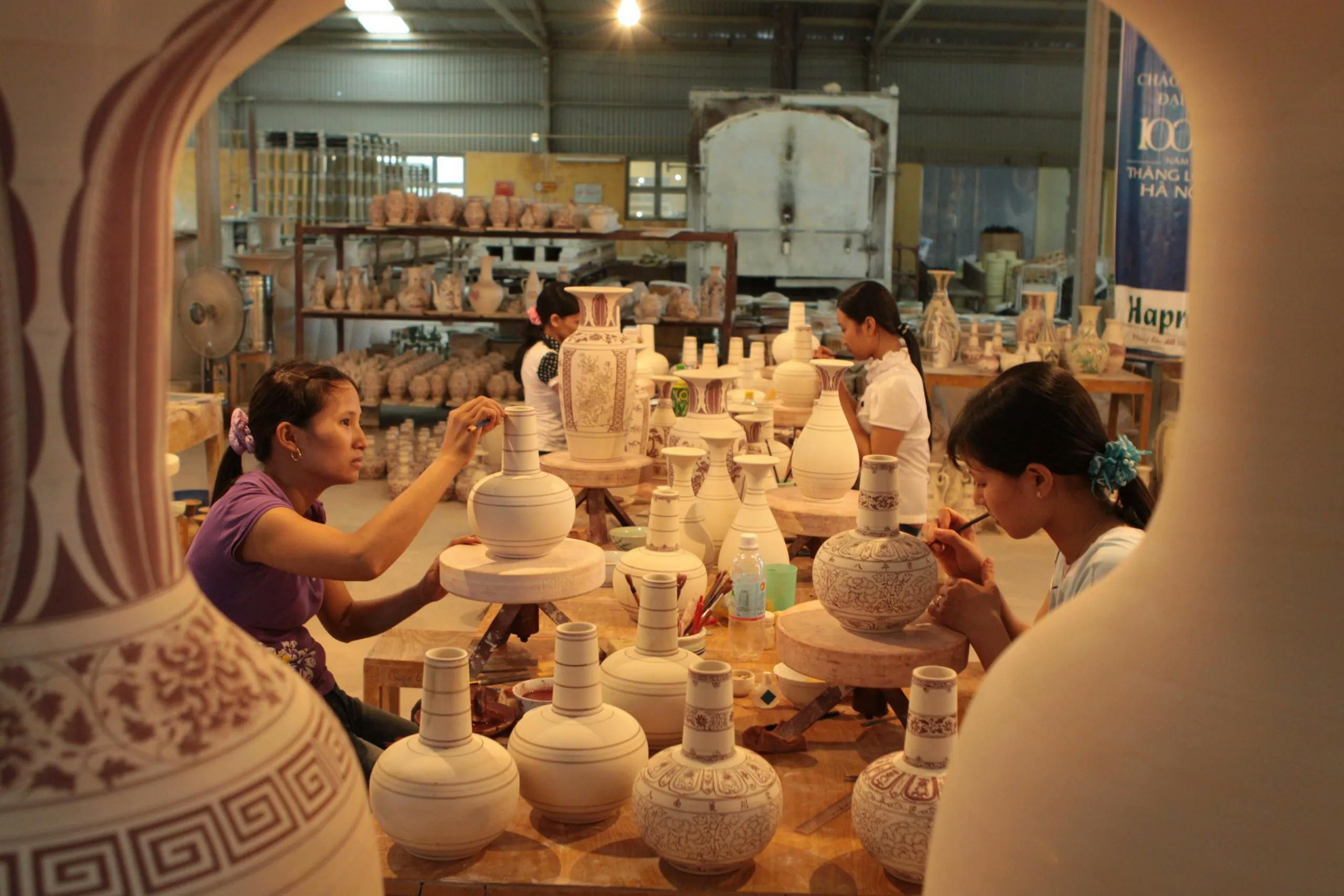 Artists are painting and decorating ceramic vases